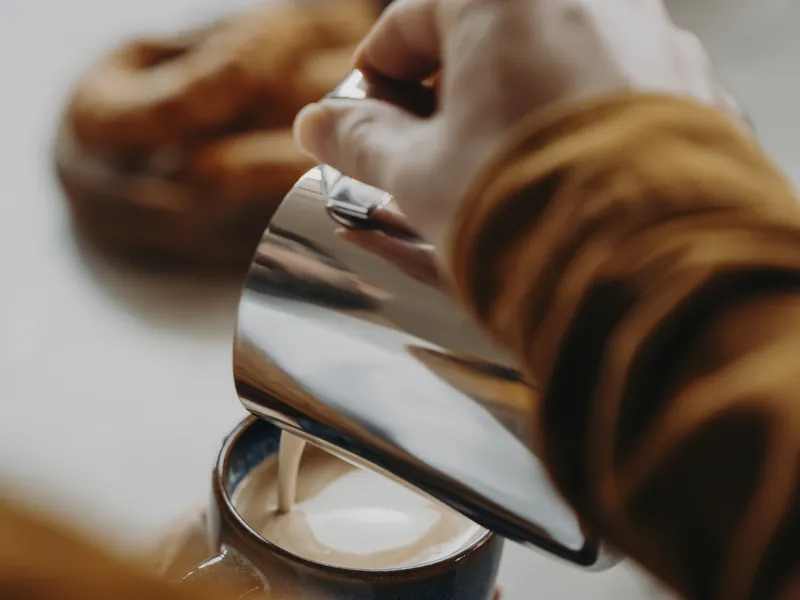 Milchschaum wird in eine Tasse gegossen